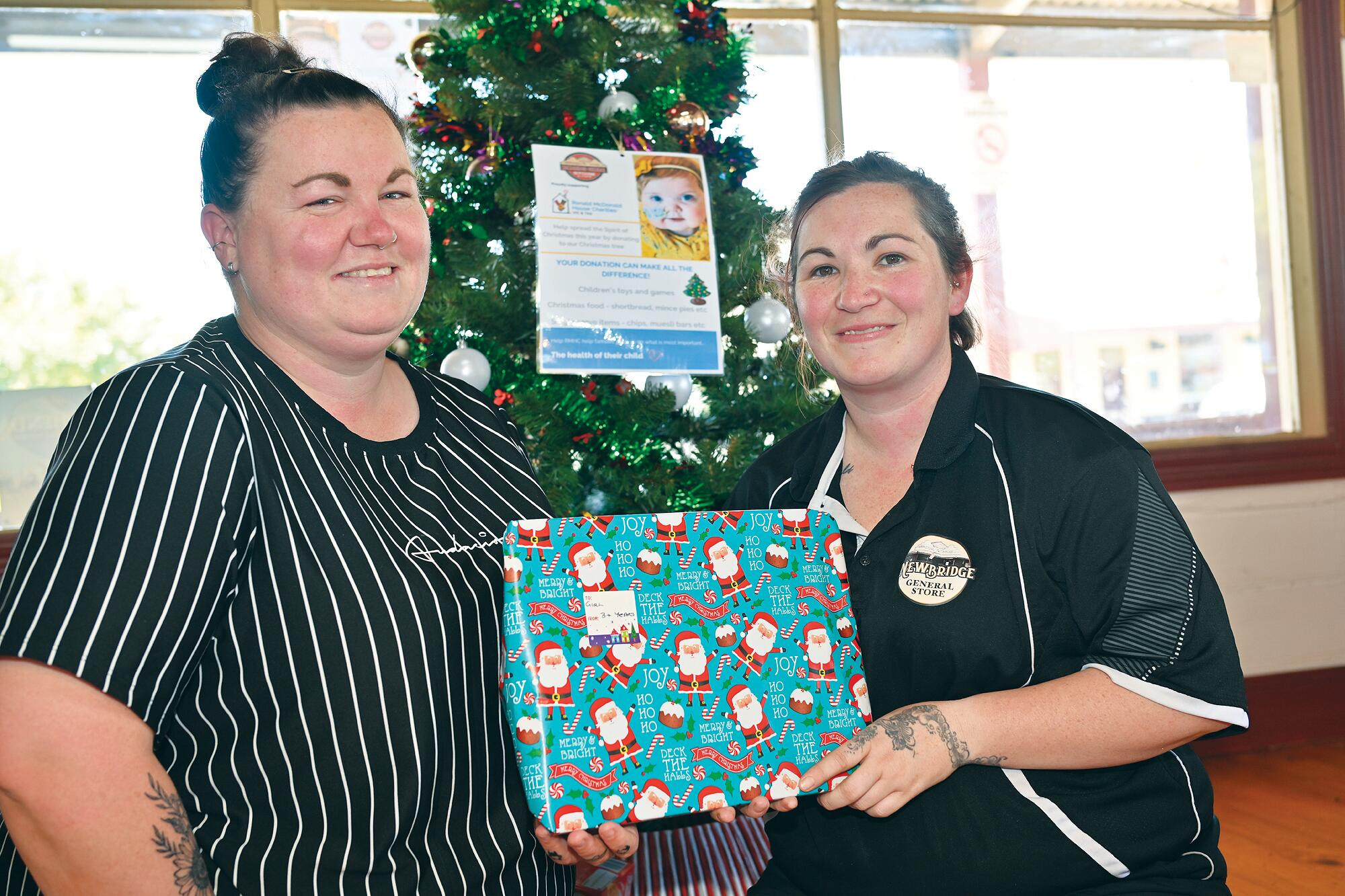 Gifts for the children: Jaydene Burzacott and Kacey Davis place latest donations under the Christmas tree. LH PHOTO