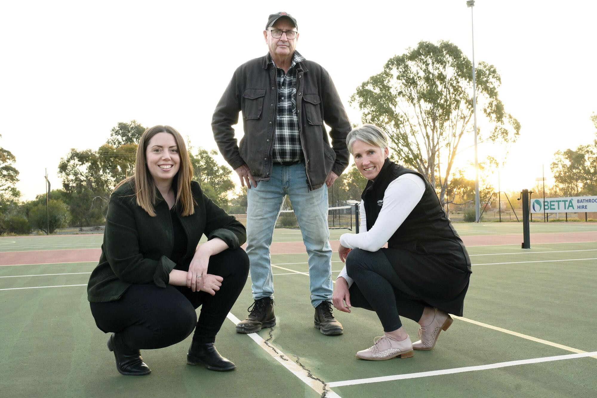 Martha Haylett inspects the cracked court surface with reserve committee president Bryan Ryan and Laura Naughton on Monday. LH PHOTO