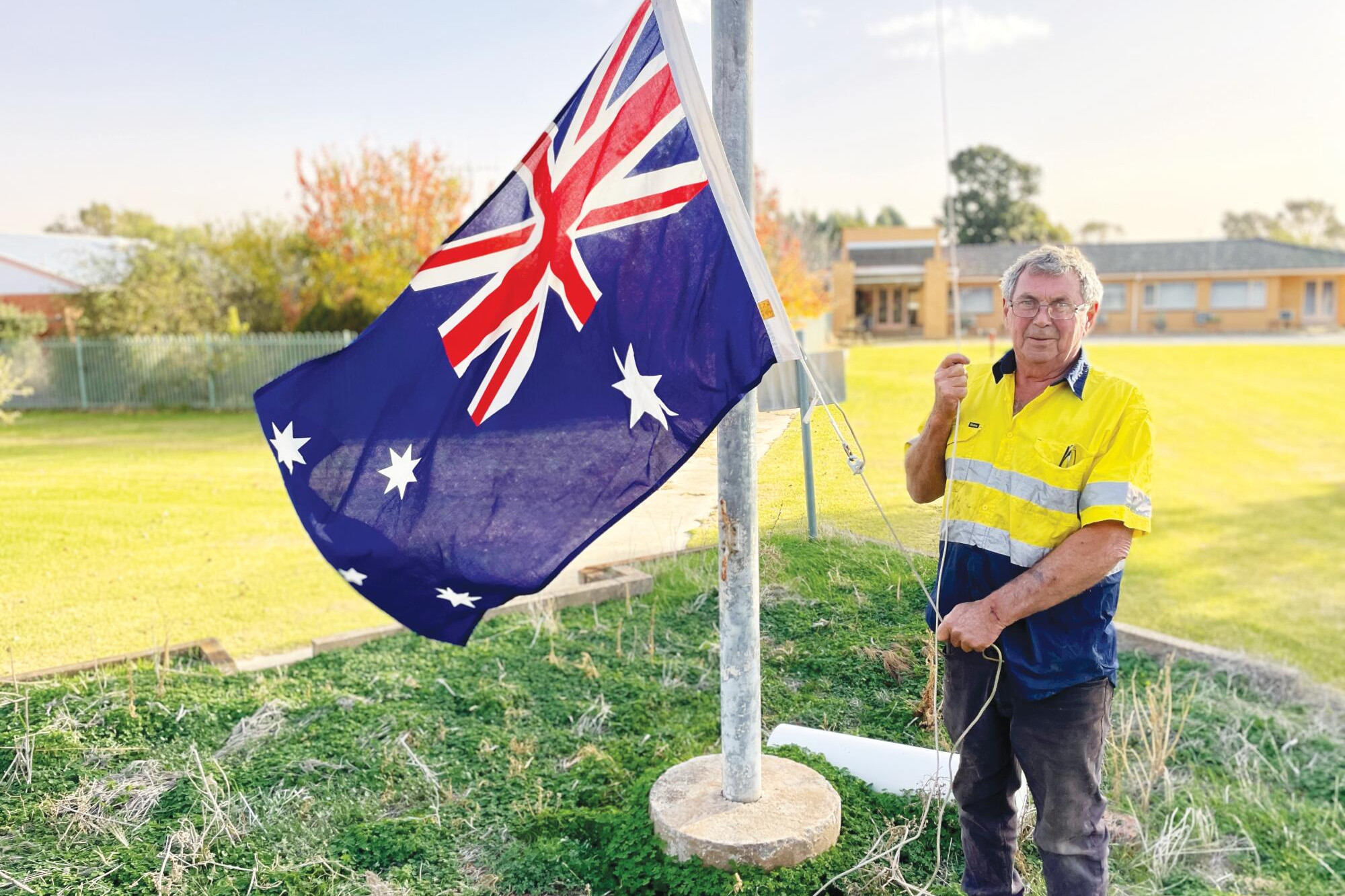 Trevor McIntosh raises the Australian flag outside the former aged care hostel to signify its return to the community